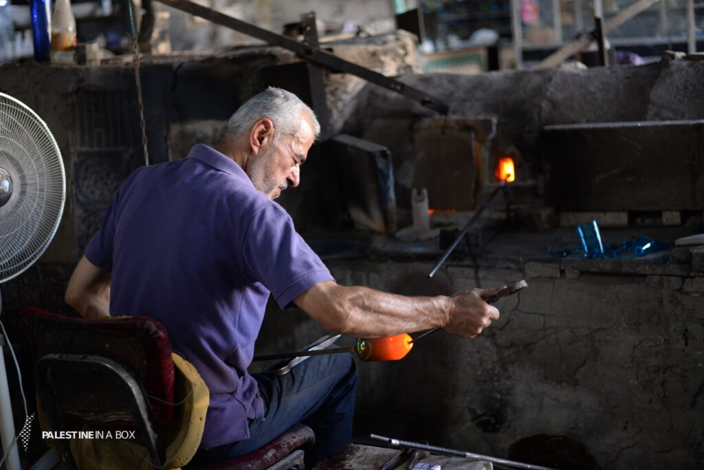 The Art of Glass-Blowing 4 The man puffs and blows into the pipe until he achieves the desired shape, which is then held by a pair of pliers.